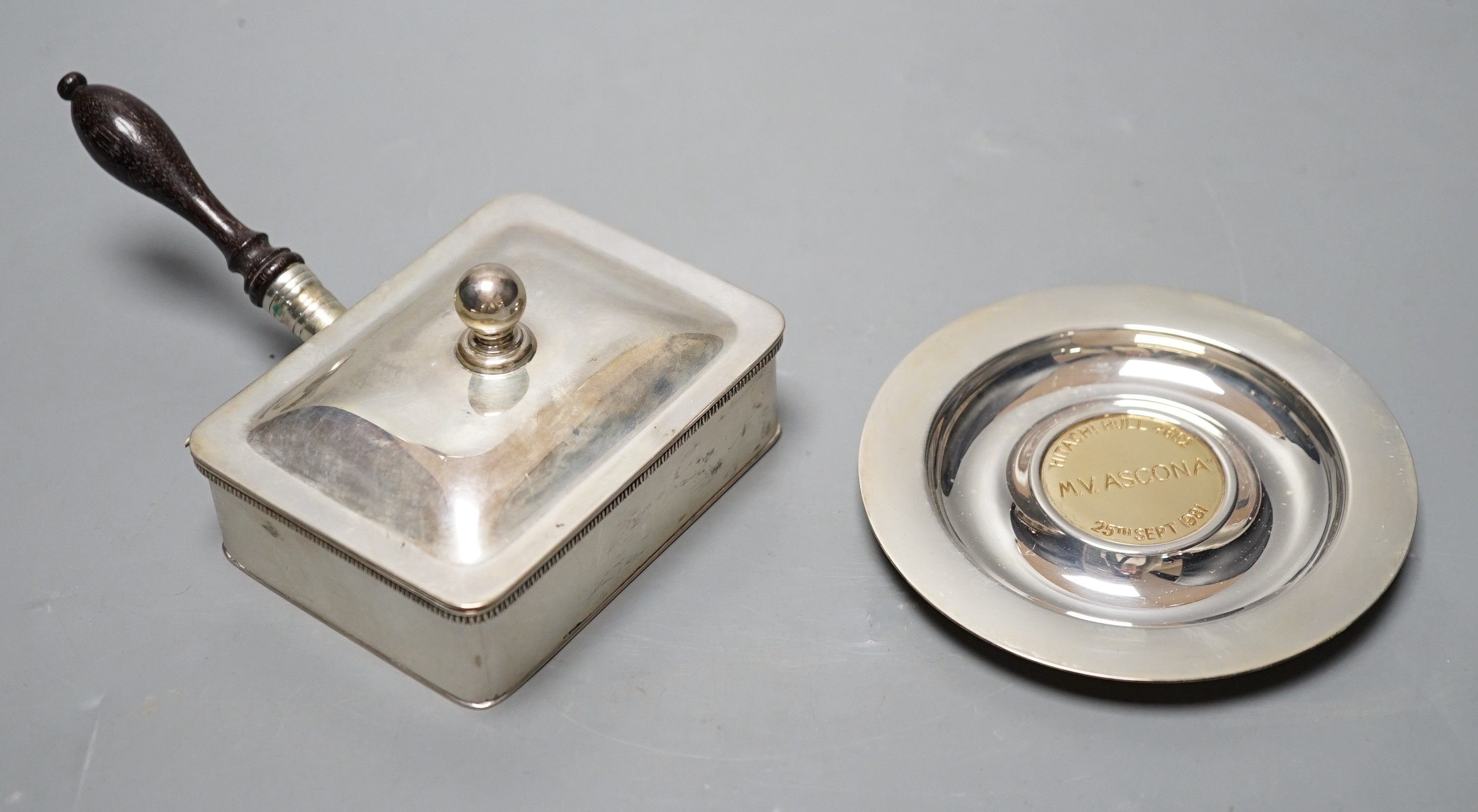 A modern silver cigarette box, with turned wooden handle, Birmingham, 1955, 14.7cm and a modern silver Asprey dish, with engraved yellow metal central plaque, gross 8.6oz.